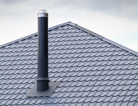 Metal tile roof and metal chimney. Chimney on the roof of the house.